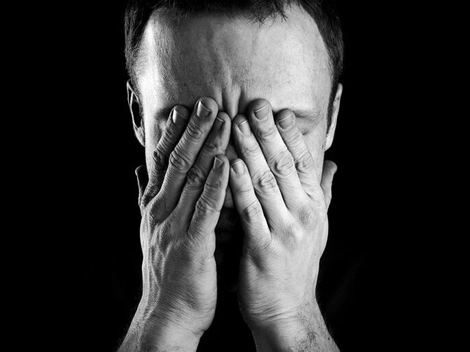 a man covers his face with his hands when refusing alcohol